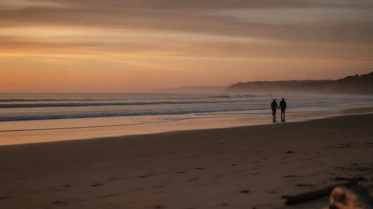 Casal a caminhar na praia ao anoitecer, ao longe